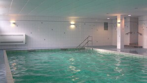 Ein Innenpool mit klarem Wasser, gefliesten Wänden und einer Leiter zum Ein- und Ausstieg.