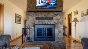 A stone fireplace with a television mounted above it. - Ranch Home w/ Rolling Hill Views & Hot Tub (Harman)