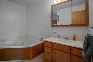 Une salle de bain avec une baignoire, des meubles en bois, un lavabo et un miroir avec éclairage.