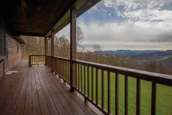 Une terrasse en bois avec une balustrade donnant sur un paysage montagneux.