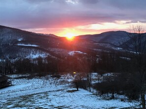 Un paysage enneigé avec un coucher de soleil sur une chaîne de montagnes.