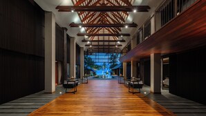 A spacious corridor with wooden flooring, a high ceiling with exposed beams, and a view of a tropical landscape through a large window. - Villa Akatsuki (Koh Samui)