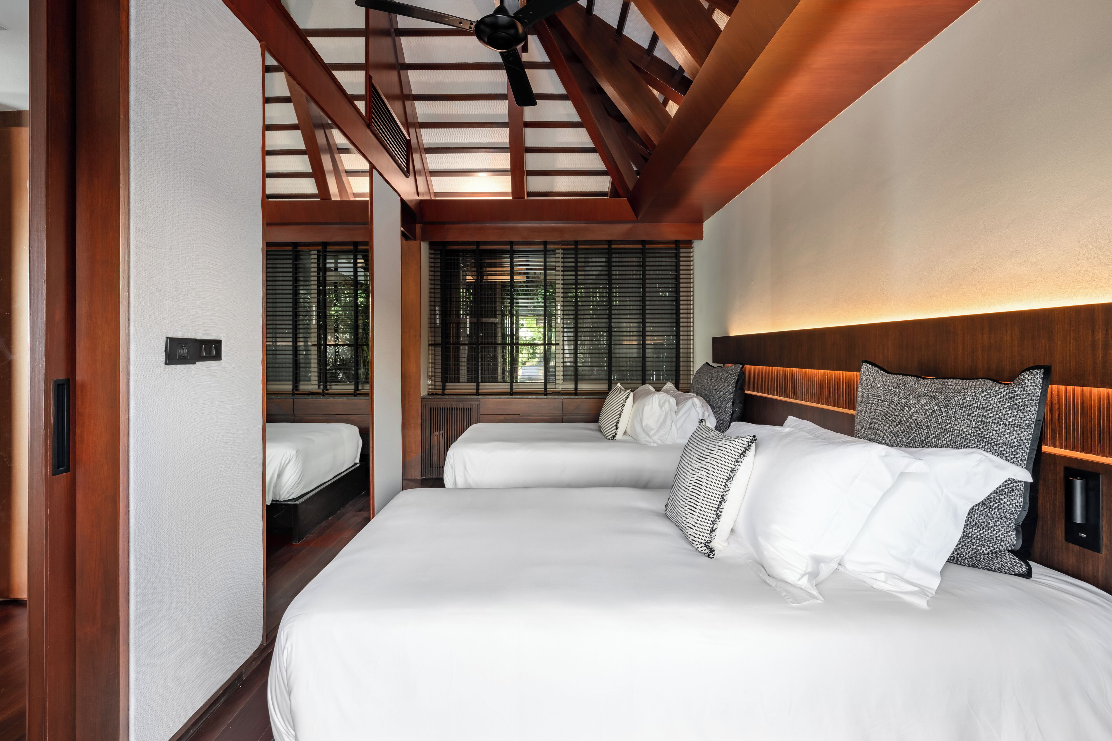 A hotel room with a large bed, a ceiling fan, and a window with blinds.