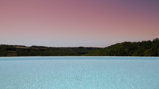 A clear view of a swimming pool with a natural landscape in the background.