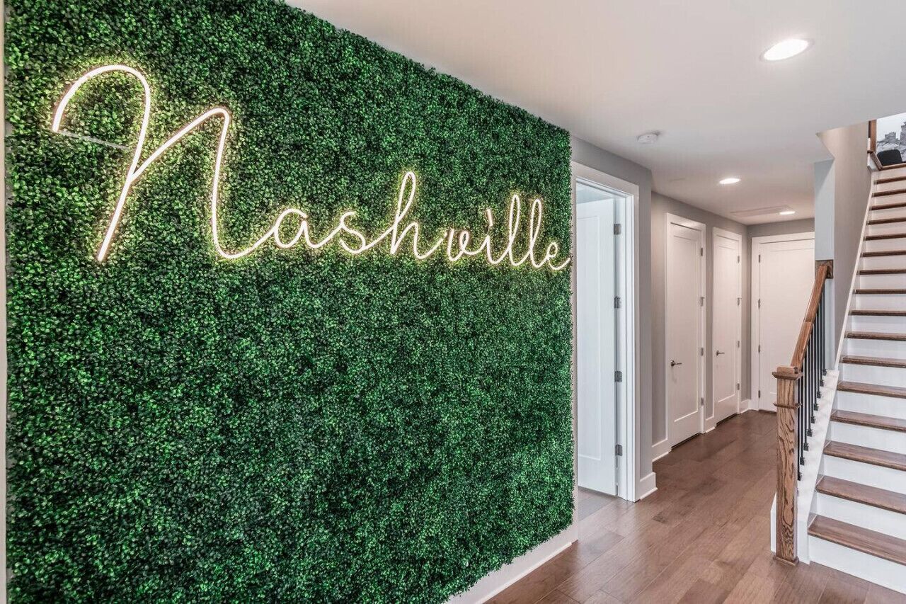 Un mur à la texture verdoyante et feuillue, sur lequel le mot « Nashville » est écrit en lettres lumineuses.