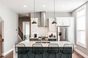 A modern kitchen with a central island, pendant lighting, and a stainless steel range hood. - Summer Discount at Nashville City View (Nashville)