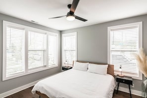 A bedroom with a bed, a nightstand, a lamp, and a ceiling fan.