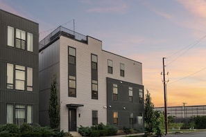A modern two-story building with a flat roof, large windows, and a balcony.
