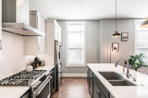 A modern kitchen with a gas stove, stainless steel appliances, and a large window with blinds. - Summer Discount at Nashville City View (Nashville)
