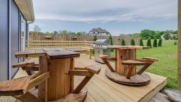 Un patio al aire libre con mesas de madera y una parrilla.