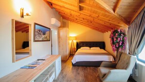 Un dormitorio con techo de madera, una cama, una mesita de noche, una silla, un espejo y un aire acondicionado fijado a la pared.