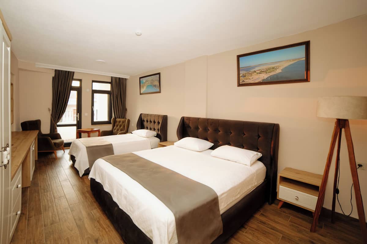 A hotel room with two beds, a desk, a chair, a lamp, and a painting on the wall.