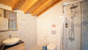 Un baño con techo de madera, papel tapiz estampado, un lavabo blanco, un inodoro y una zona de ducha.