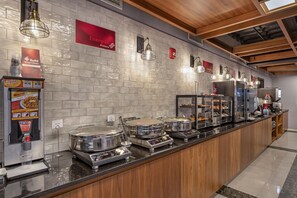 A buffet area with self-service stations, including a waffle maker and a beverage dispenser. - Best Western Plus Soho Hotel (New York)