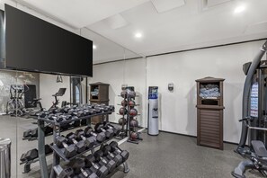 A gym with exercise equipment, a water dispenser, and a television. - Best Western Plus Soho Hotel (New York)