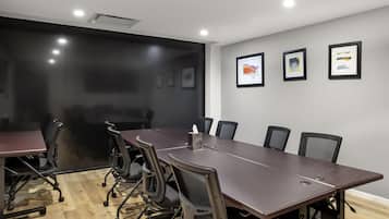Uma sala de conferências com uma mesa comprida, seis cadeiras e três obras de arte emolduradas na parede.