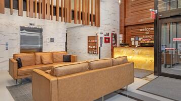 A modern lobby with a reception desk, a sofa, and a wall-mounted elevator.