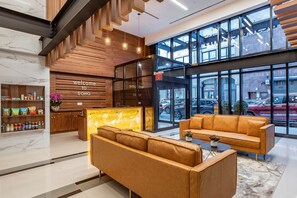 A modern lobby with a reception desk, seating area, and large windows offering views of the street. - Best Western Plus Soho Hotel (New York)