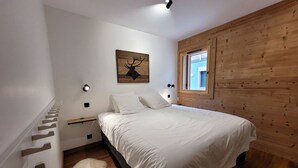 Ein Schlafzimmer mit Bett, Holzwand, Fenster und Wandbild sowie einem kleinen Teppich.