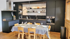 Eine kompakte Küche mit modernen Geräten, ein Essbereich mit Tisch für vier Personen und ein eingebauter Backofen.