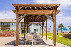 Eine hölzerne Pergola mit einem Schild, das „Rauchen verboten und Parkausweise erforderlich“ anzeigt, über einem Patio mit Tischen und Stühlen.