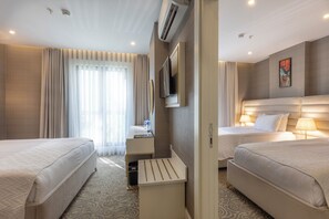 Hotellihuone, jossa on kaksi sänkyä, televisio, työpöytä tuolilla ja kylpyhuoneen ovi.