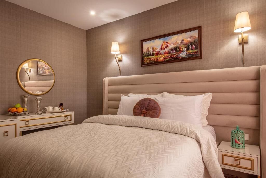 Un dormitorio con una cama grande, un aparador, un espejo y dos lámparas de pared.