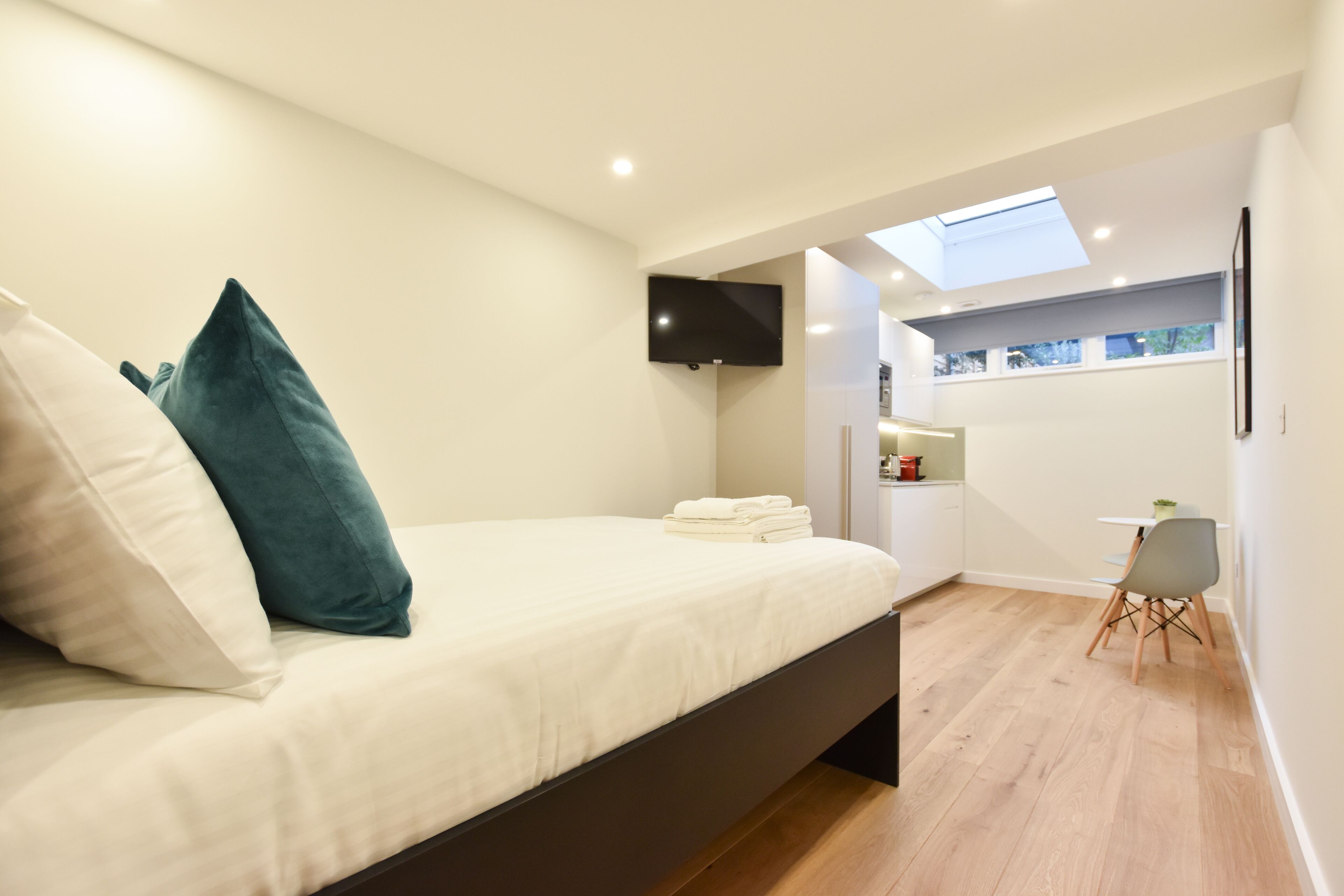 A modern bedroom with a bed, a TV, and a skylight.
