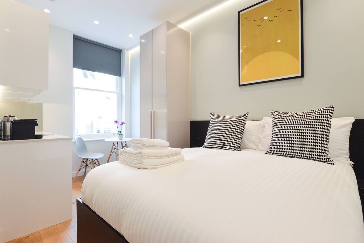 Een moderne hotelkamer met een groot bed, een klein bureau en een raam met uitzicht op de stad.
