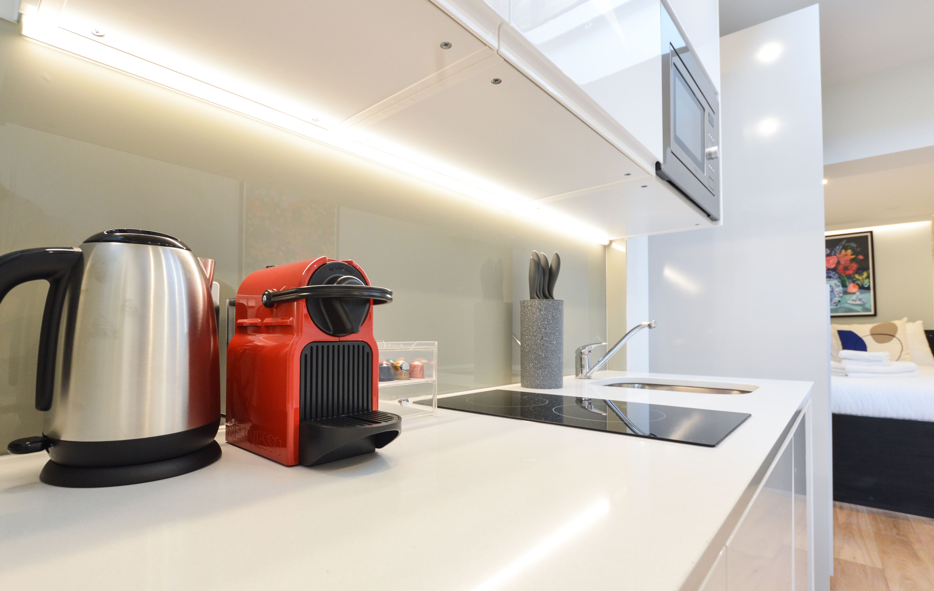 A modern kitchen with a kettle, a red appliance, and a sink.