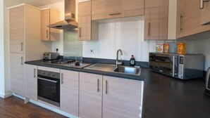 Een moderne keuken met lichte houten kastjes, roestvrijstalen apparatuur en een inbouwoven.