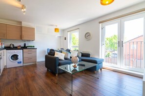 Un appartement moderne doté d’une cuisine, d’un espace de vie et de grandes portes-fenêtres coulissantes donnant sur un balcon.