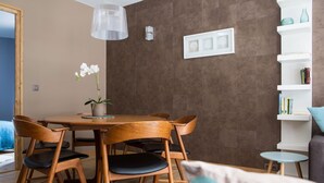 Zona pranzo con tavolo e sedie in legno, un'orchidea in vaso e un lampadario.