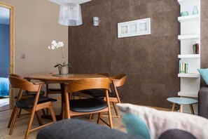 A dining area with a wooden table and chairs, a potted orchid, and a hanging light fixture.