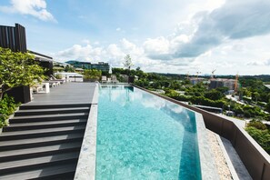 Una piscina al aire libre, sombrillas, sillones reclinables de piscina