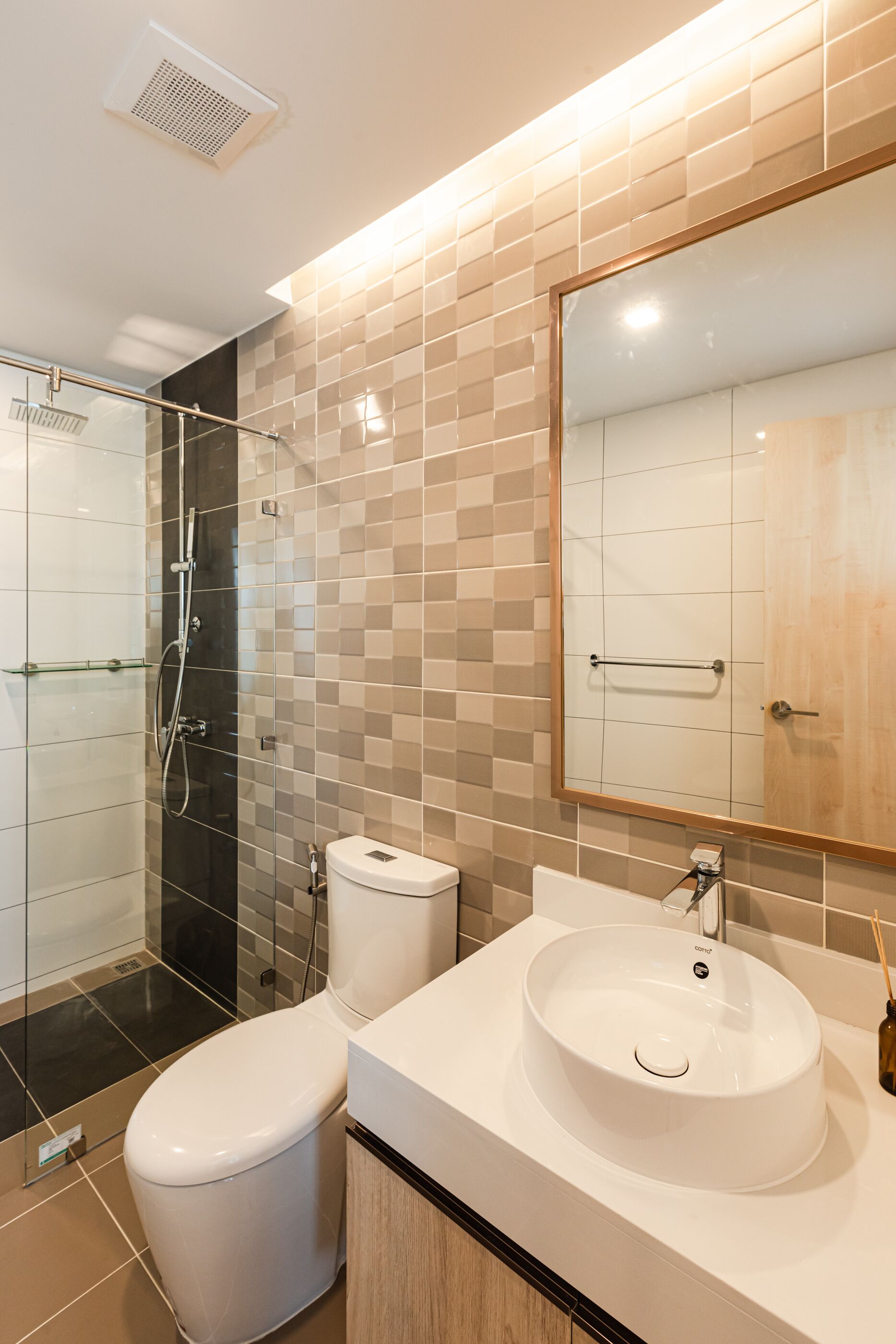 A modern bathroom with a glass-enclosed shower, a white toilet, and a large mirror above a sink.