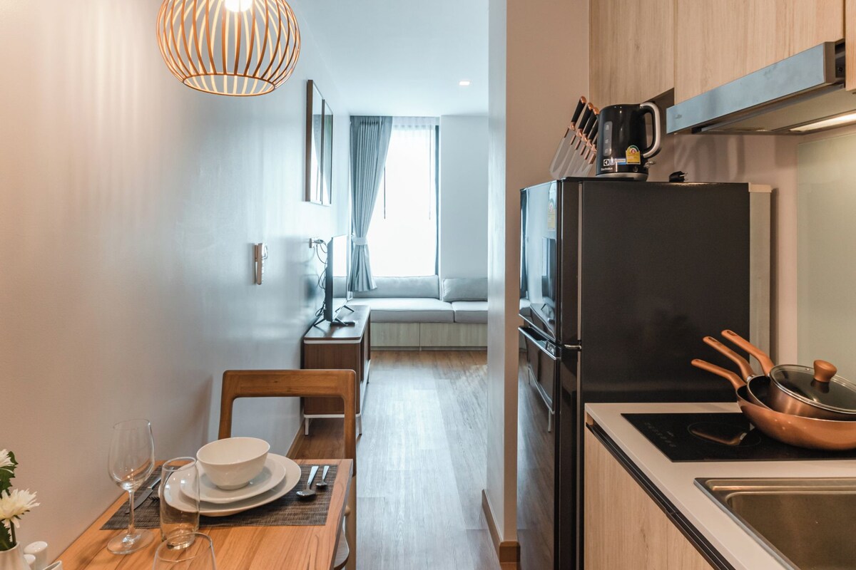 A modern kitchen with wooden cabinets, a black refrigerator, and a dining area with a wooden table and chairs.