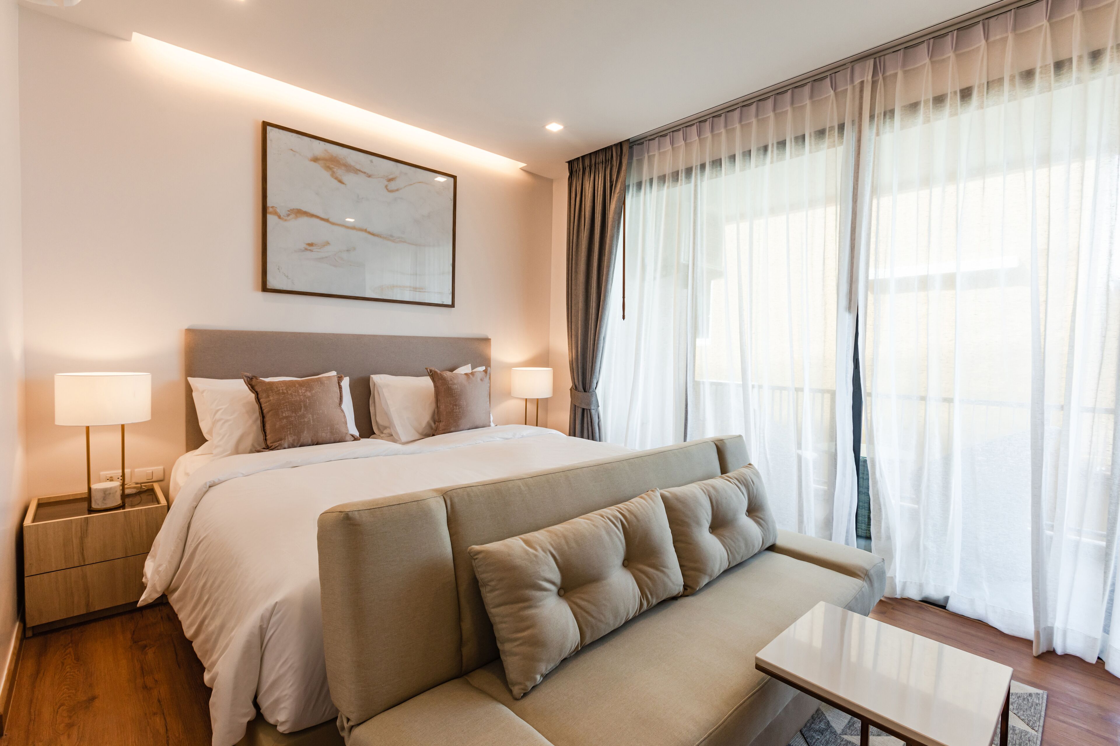 Una habitación de hotel con una cama grande, un sofá, una mesita de noche y un tocador.