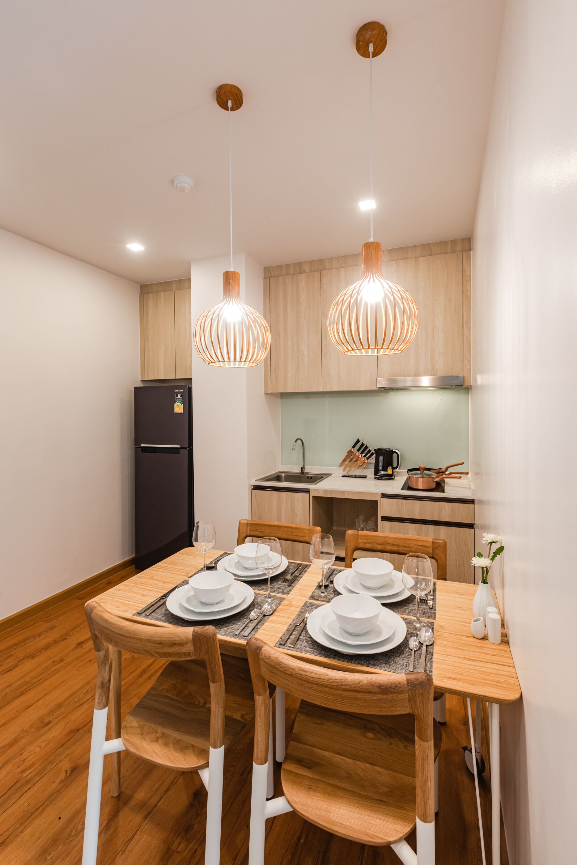 A modern kitchen with wooden cabinets, a black refrigerator, and a dining area with a wooden table and chairs.
