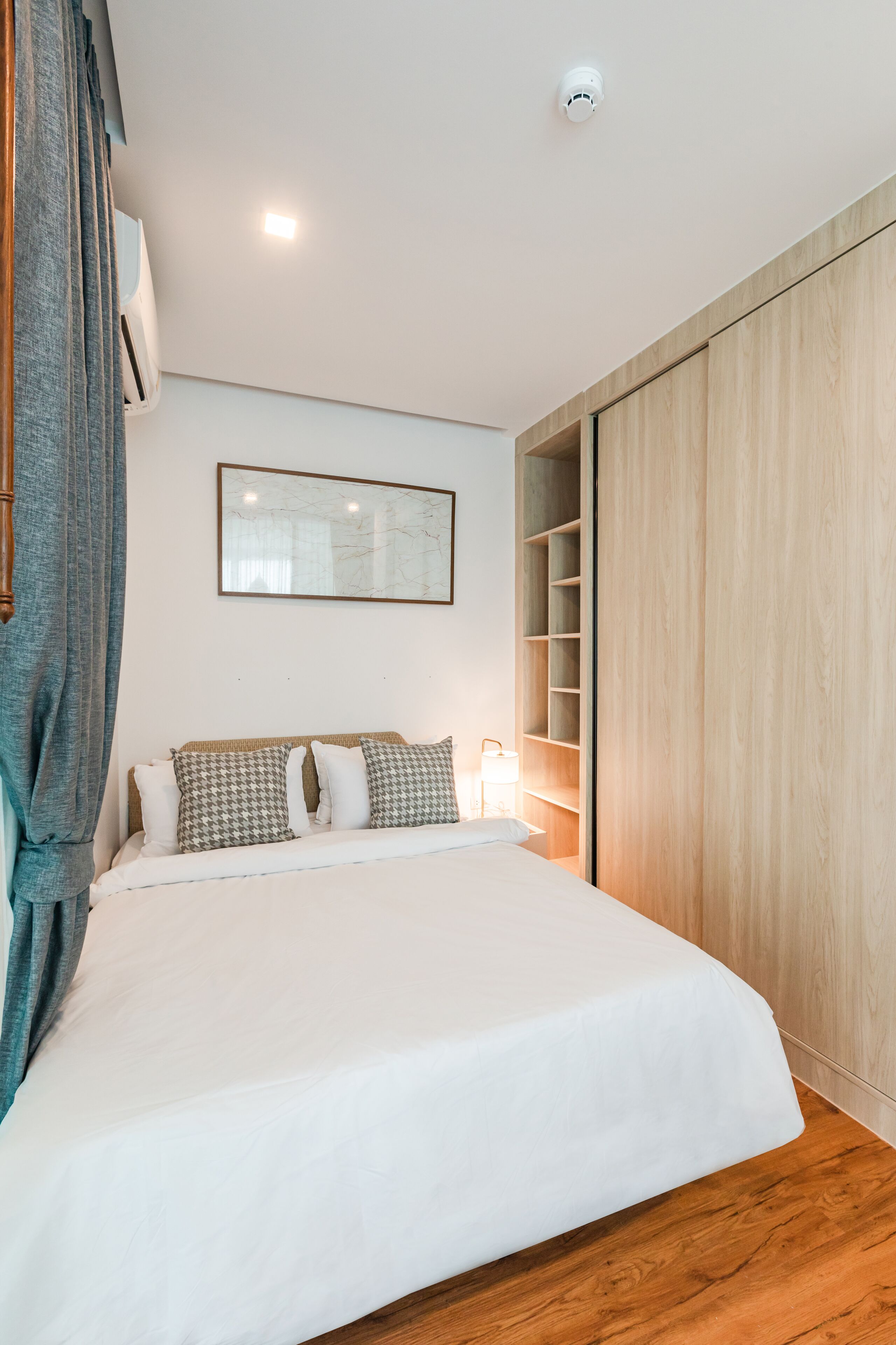 Une chambre à coucher avec un grand lit, une armoire, une table de chevet et un climatiseur fixé au mur.