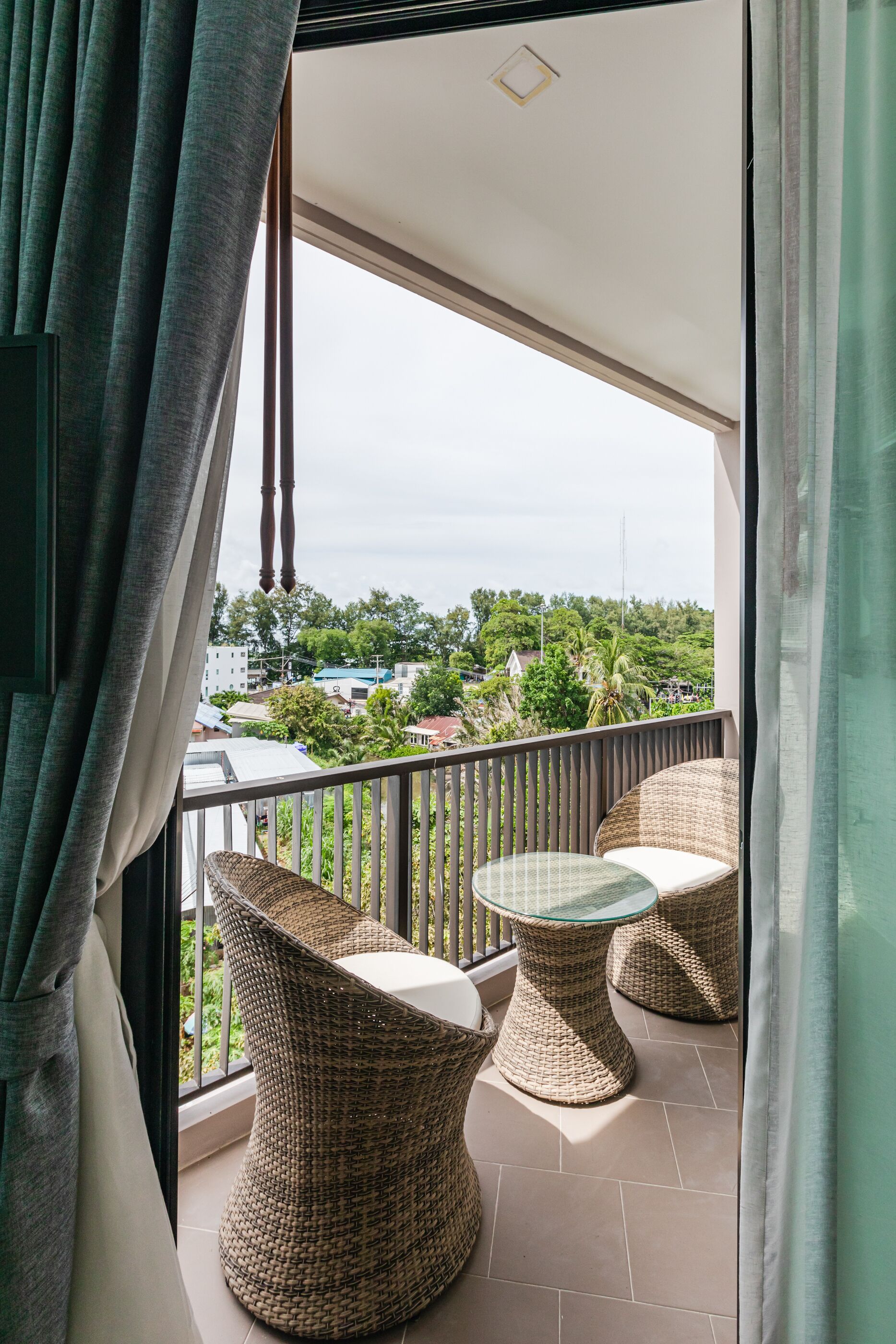 A balcony with wicker furniture and a view of a cityscape.