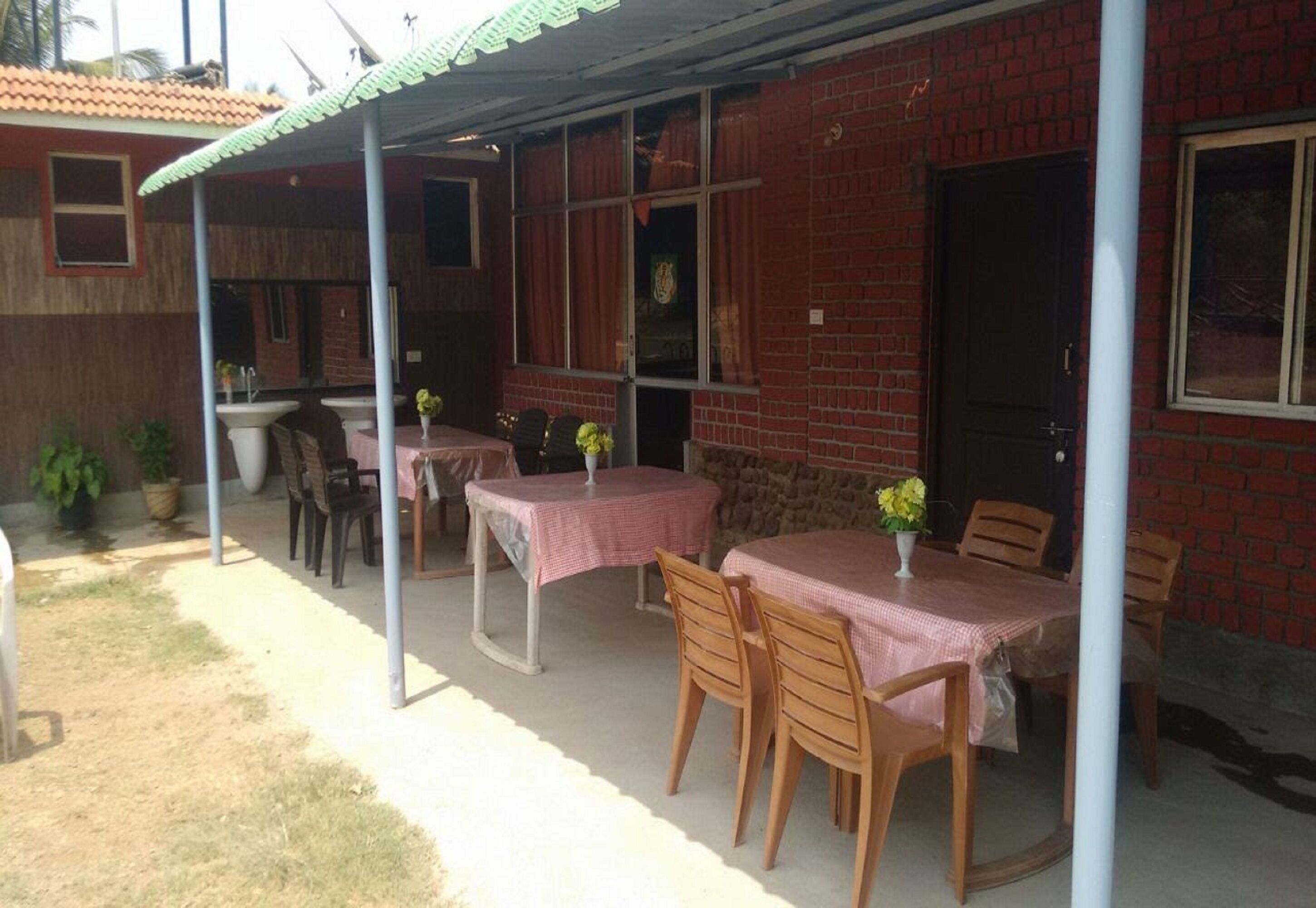 Een buitenterras met tafels en stoelen, een overdekt zitgedeelte en een gebouw van baksteen op de achtergrond.