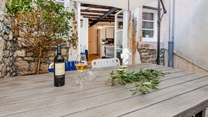 Una mesa de madera con una botella de vino, una copa y una rama de follaje.