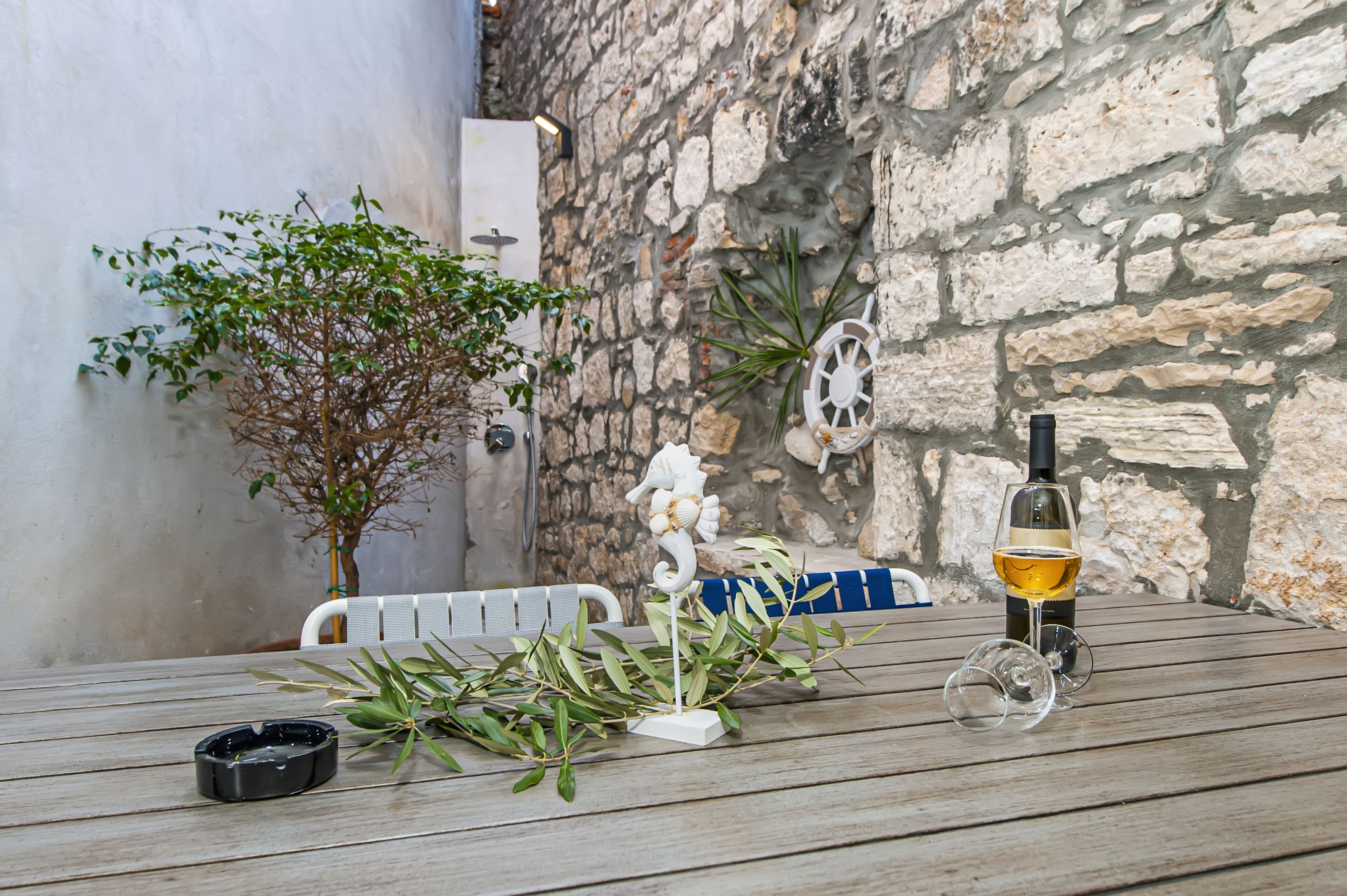 Een houten tafel met een fles wijn, een glas en een plant.