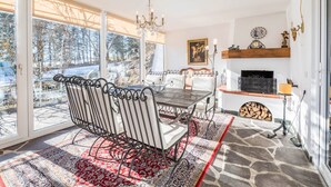 A dining area with a metal table and chairs, a fireplace, and a view of the outdoors. - Apartment "Im Haus Stöckl" with Mountain View, Garden, Terrace & Wi-Fi (Angerberg)