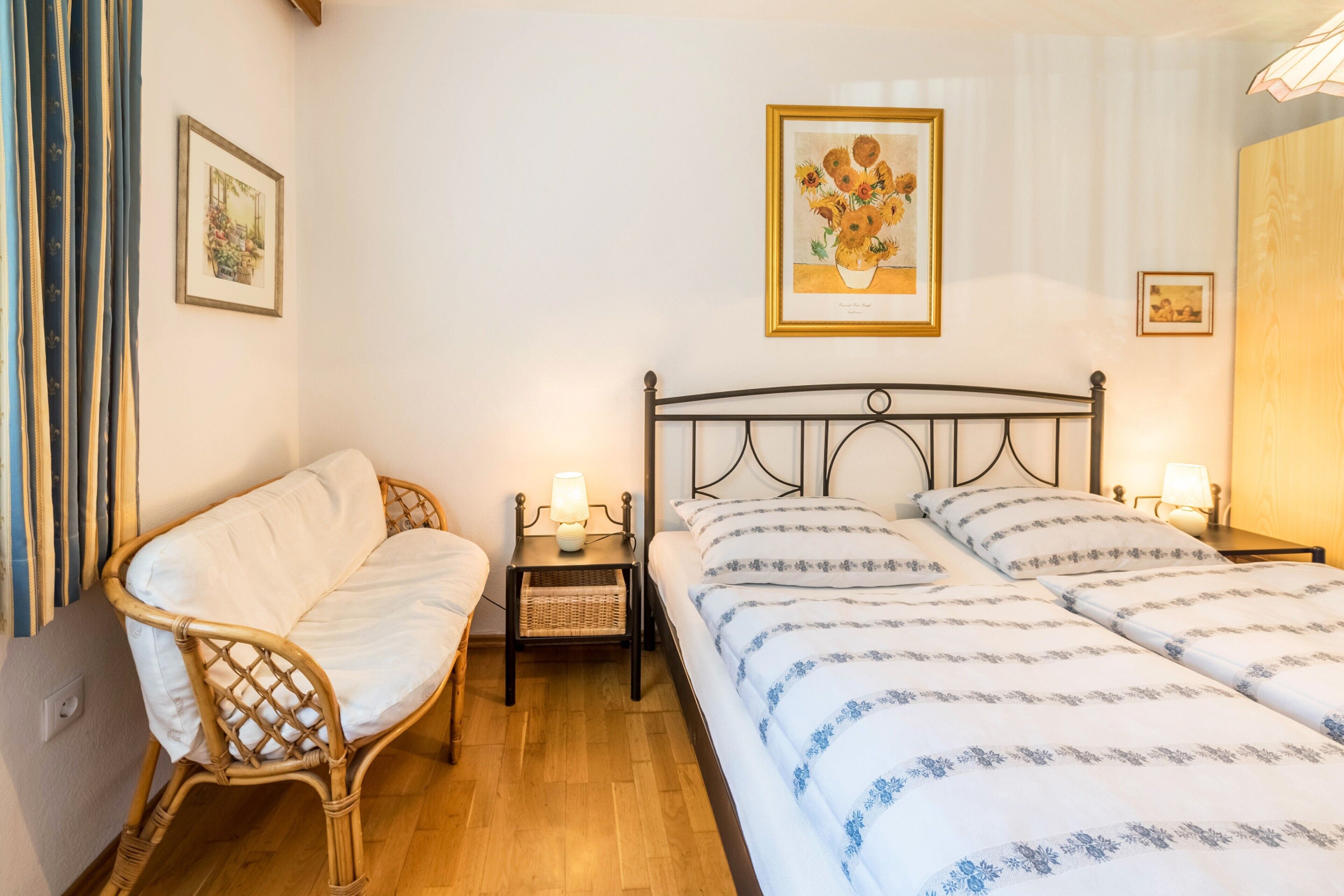 A bedroom with a bed, a chair, a nightstand, and a wall-mounted picture.