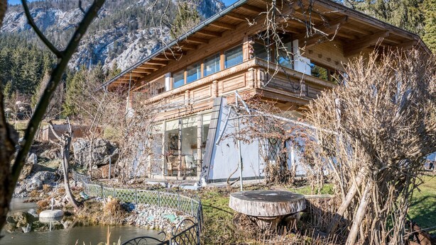 A wooden cabin with a balcony, surrounded by trees and a mountain backdrop. - Apartment "Im Haus Stöckl" with Mountain View, Garden, Terrace & Wi-Fi (Angerberg)