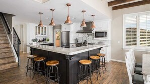 A kitchen with a central island, bar stools, and copper pendant lighting. - Hill-top Haven w/ Heated pool & spa, expansive views and more! (Sedona)