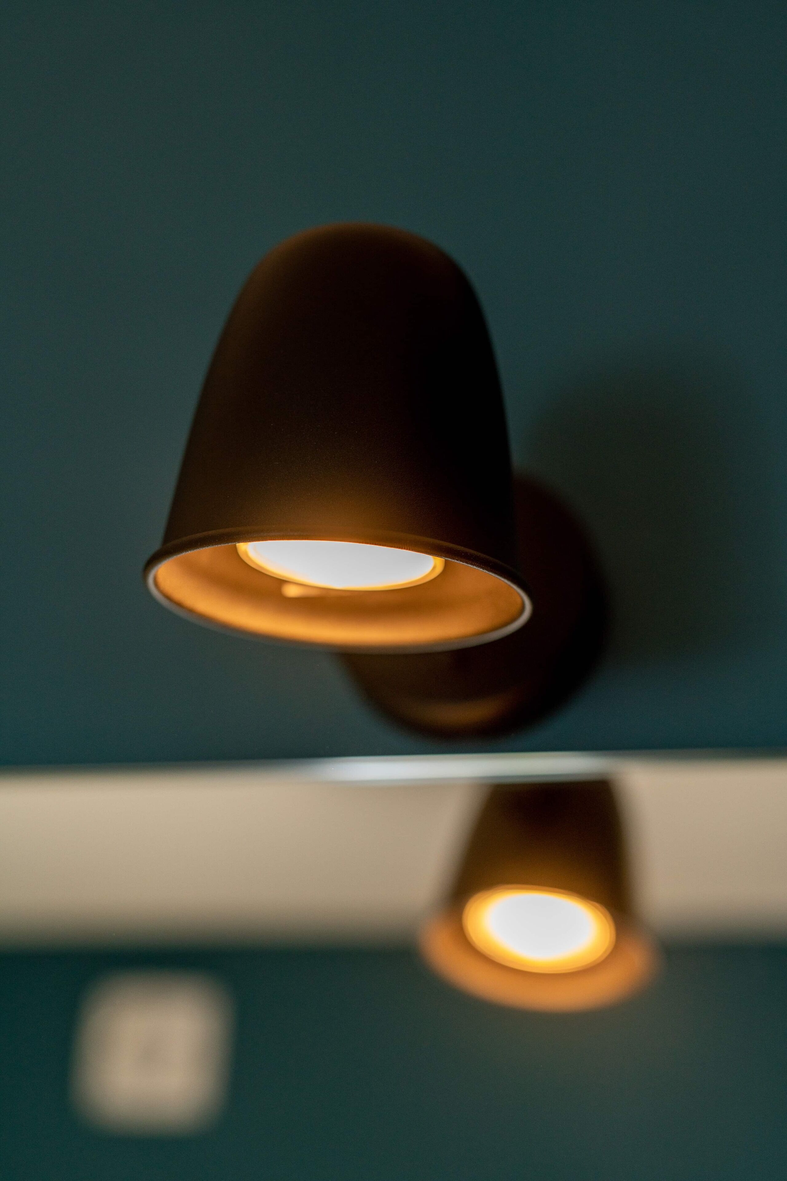 Una lámpara de pared con pantalla cónica y luz cálida.