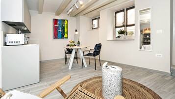 Una cocina moderna con armarios blancos, microondas y un comedor con mesa redonda y sillas.